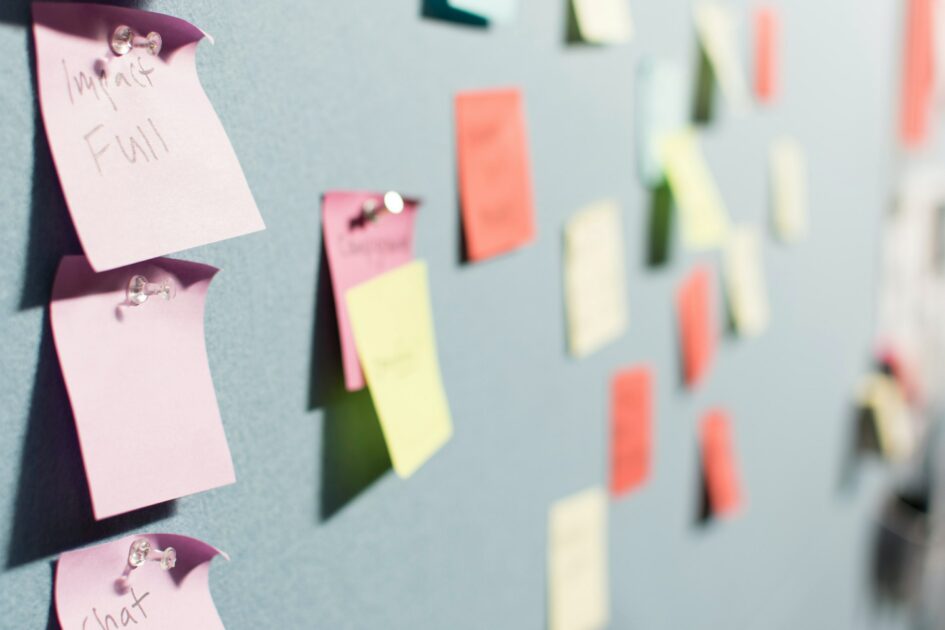 multiple coloured post it notes (pink, green and red) pinned on a blue wall.
